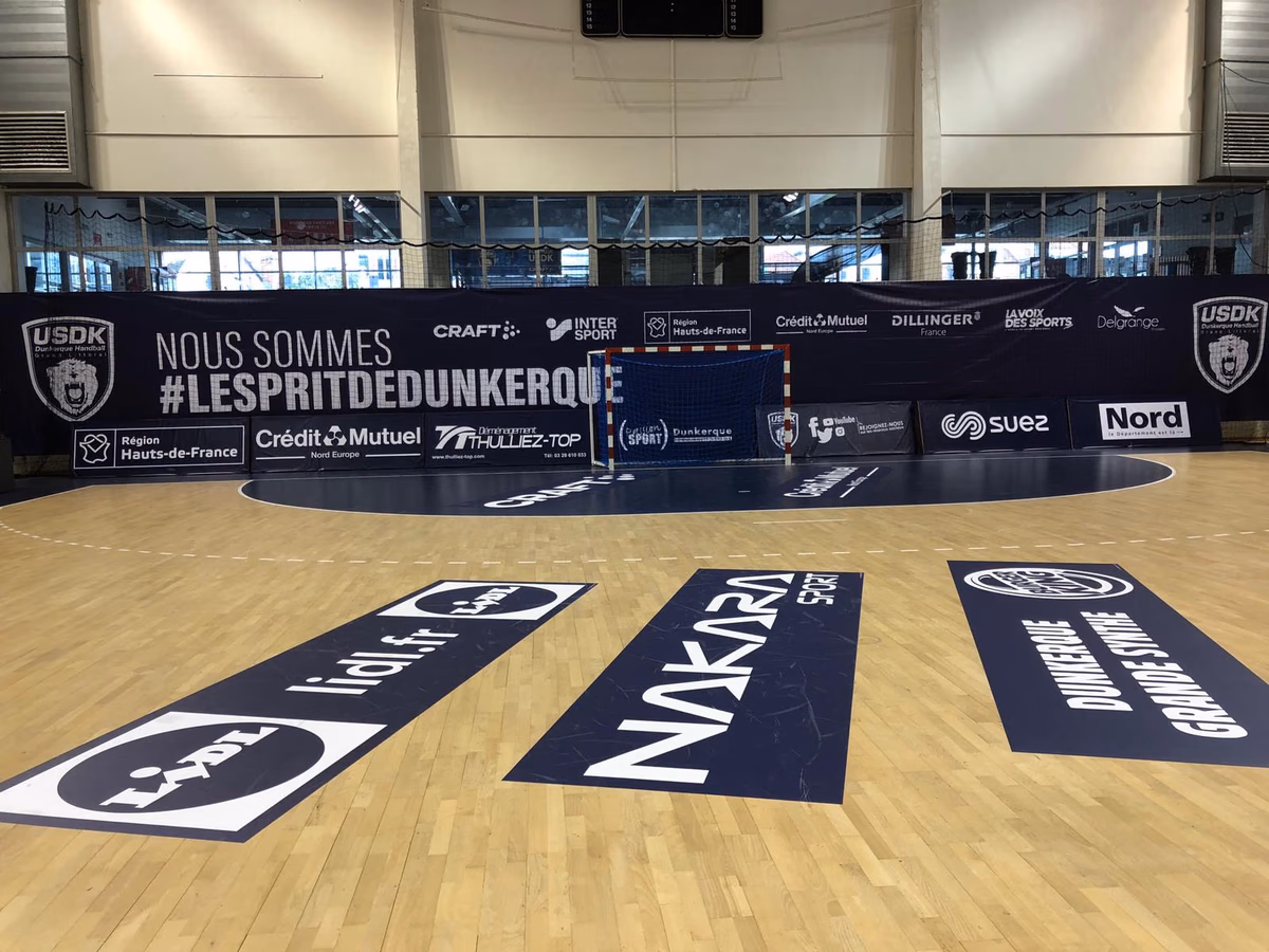 Vinilos publicitarios rectangulares en el suelo junto a la portería de una pista de balonmano