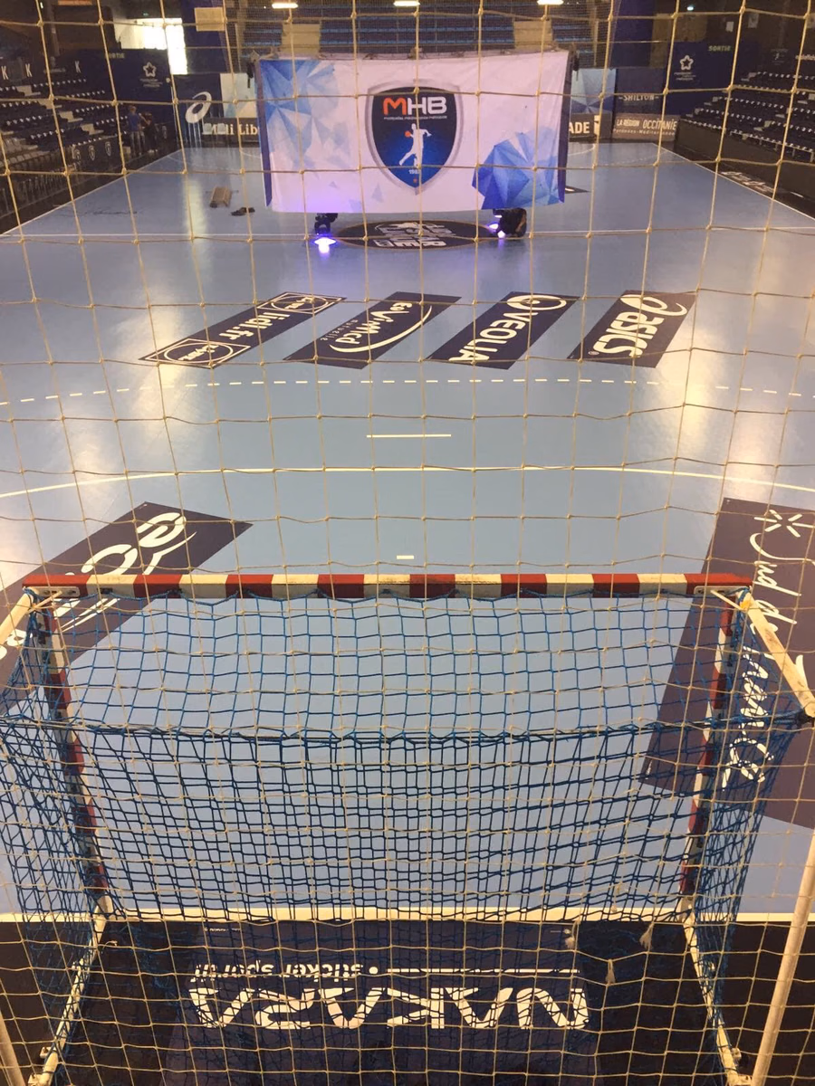 Pista de balonmano con vinilos publicitarios en el suelo y portería, vista vertical del pabellón