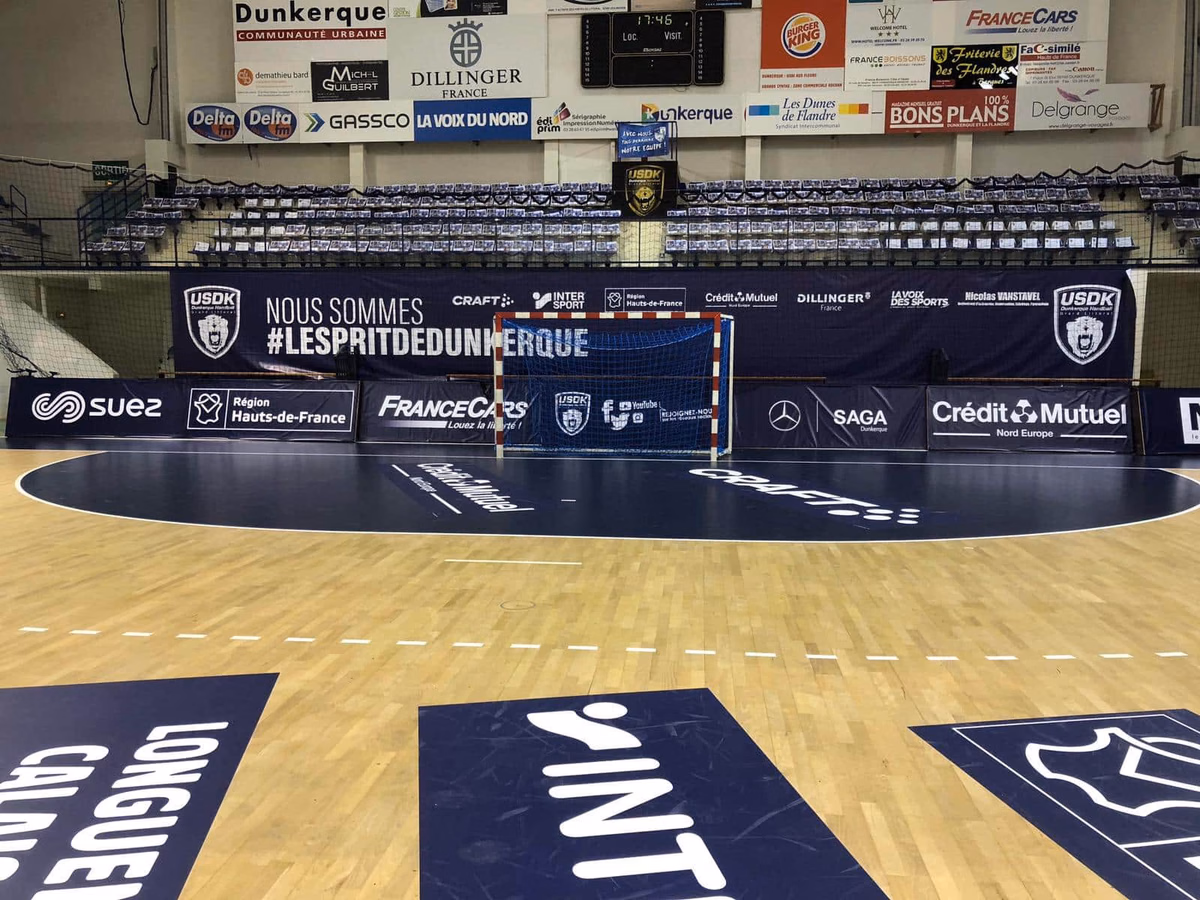 Portería de balonmano y vinilos publicitarios en el suelo de una pista azul